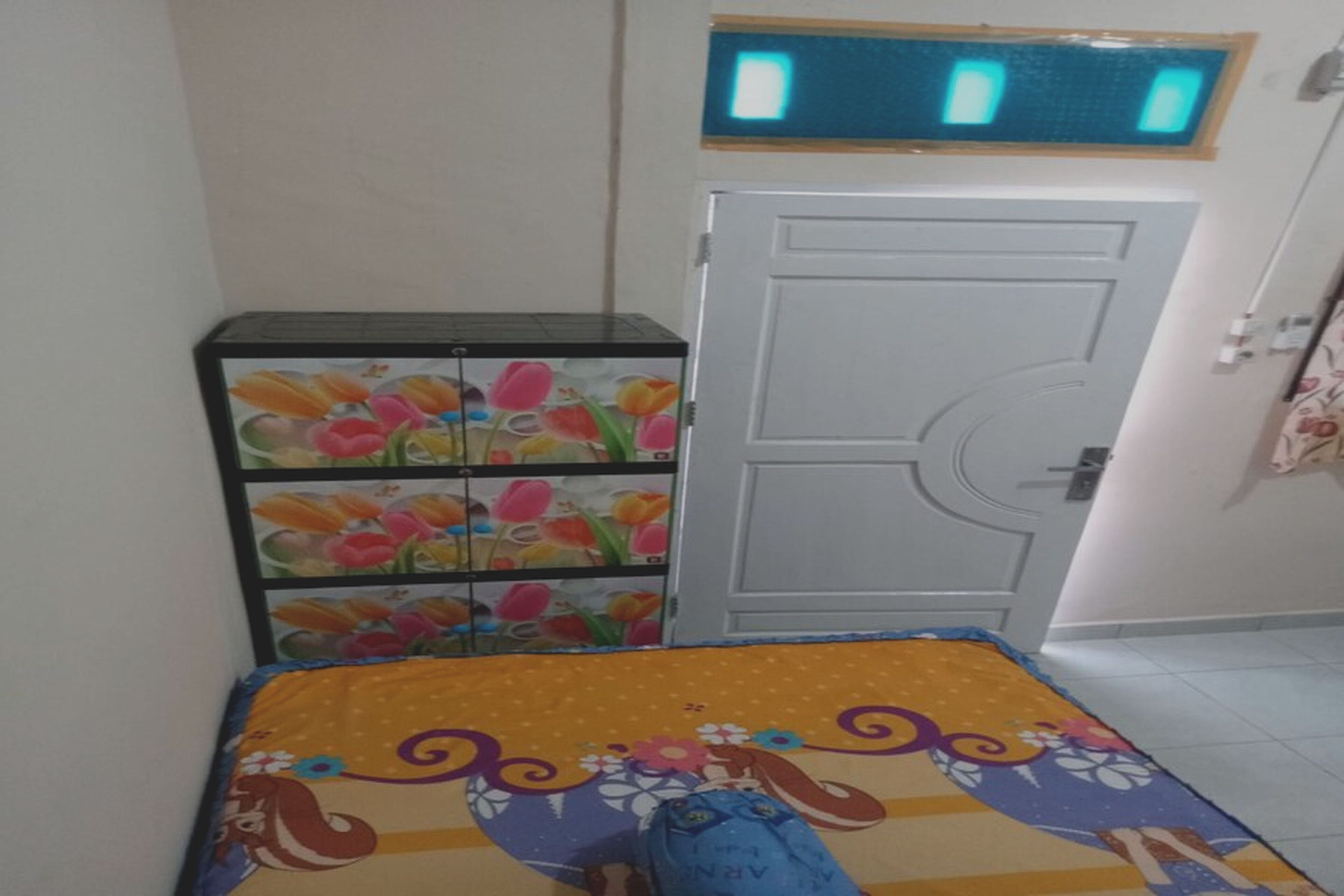 Een kamer met een bed, een garderobe en een klein kastje met bloemmotieven.