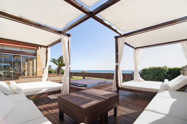 Un espace extérieur abrité comprenant une piscine, des chaises longues et une vue sur la mer.
