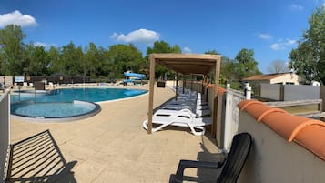 Ein Pool mit Liegestühlen, einer überdachten Sitzgruppe und einer umzäunten Holzterrasse.