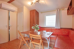 Una habitación compacta con una mesa de comedor, sillas, un sofá, una ventana con persianas y un equipo de aire acondicionado.