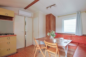 Una cocina compacta con una mesa de madera, sillas y una ventana con cortinas.