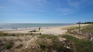 Une plage avec un rivage sablonneux, une clôture en bois et un ciel dégagé.