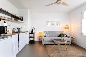 Une cuisine moderne avec des meubles blancs, un plan de travail en bois et un ventilateur de plafond.