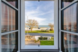 A view through a window with a clear sky, a parking lot, and a road.