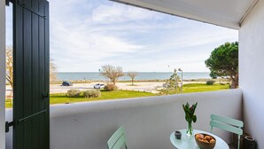 Un balcone con vista sul mare, un tavolo con un vaso e pane, e una sedia verde.