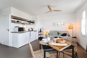 Une cuisine moderne avec des meubles blancs, un four à micro-ondes et un coin repas avec une table dressée pour deux personnes.