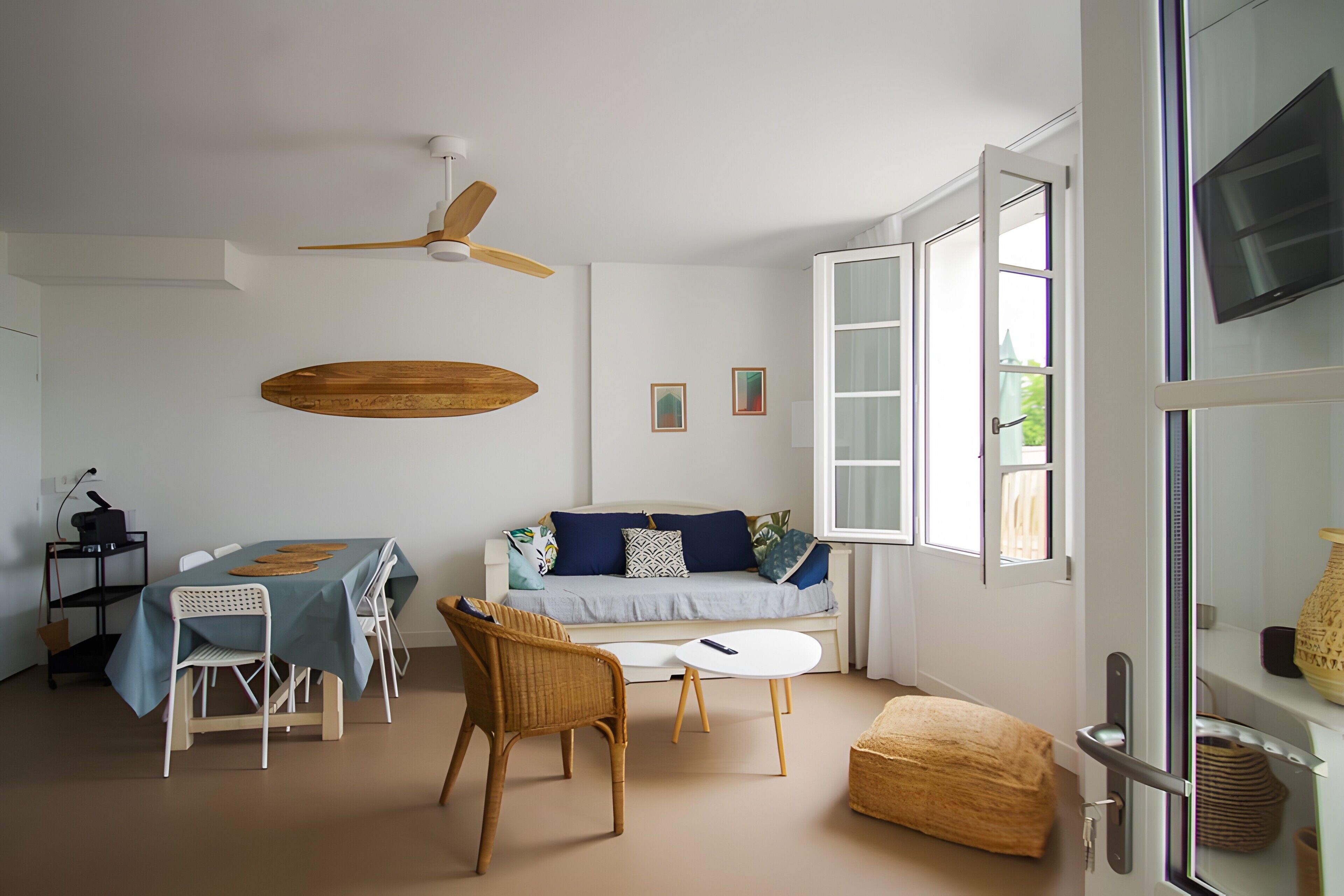 A modern living room with a dining table, sofa, chairs, and a ceiling fan.