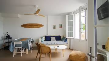 A modern living room with a dining table, sofa, chairs, and a ceiling fan.