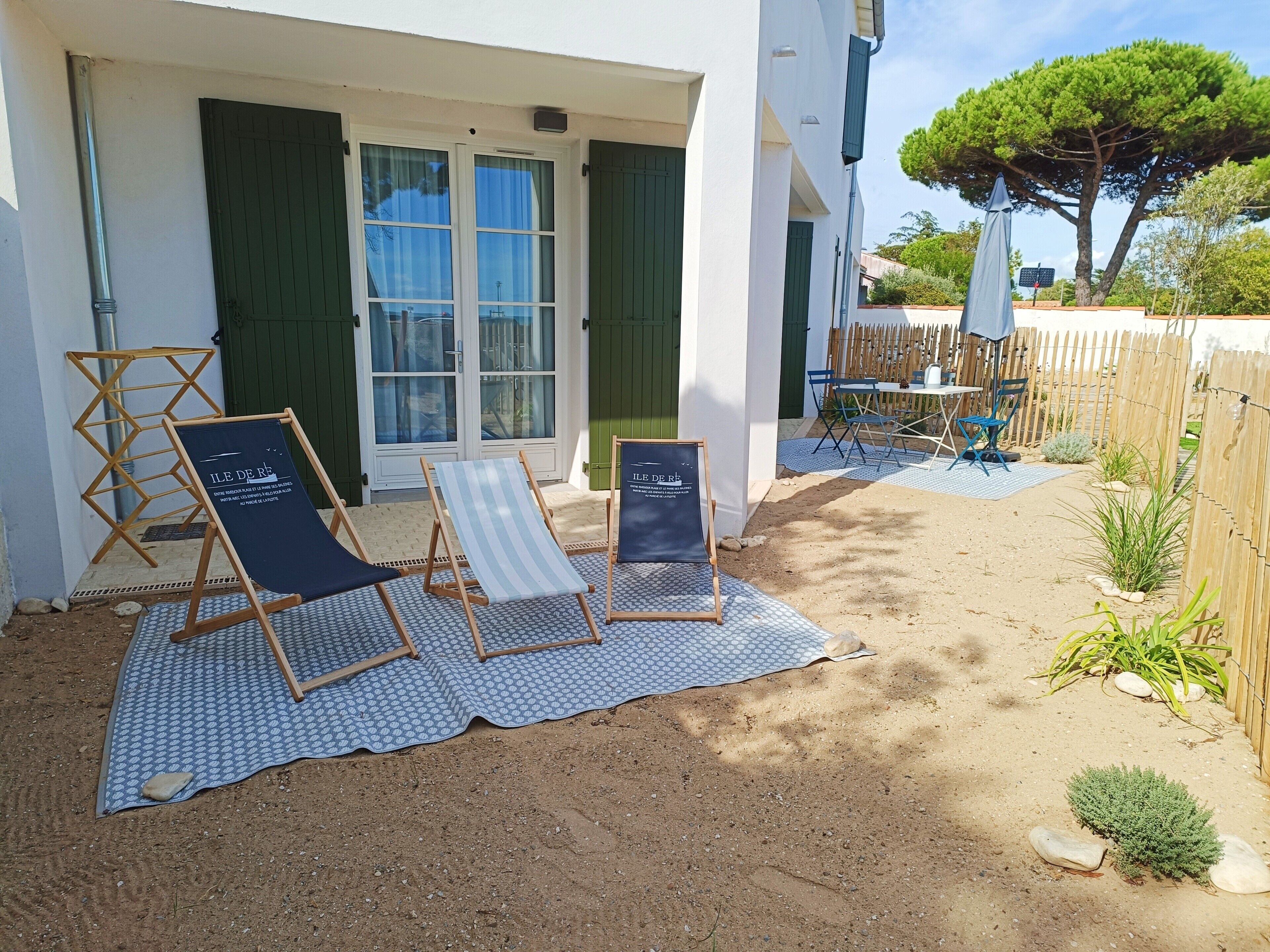 Un patio con due poltrone, un tavolo e un recinto in legno.
