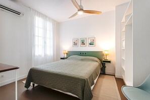 Une chambre d’hôtel équipée d’un lit, de lampes de chevet, d’un bureau et d’un ventilateur de plafond.