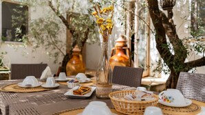 Une table dressée avec des tasses et des soucoupes blanches, ainsi qu’un vase rempli de fleurs jaunes.