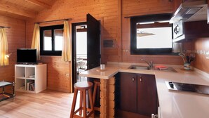 Un interior de madera con cocina, taburetes de bar, televisor y ventana.