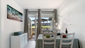 Un coin repas avec une table dressée pour deux personnes, un buffet et un tableau accroché au mur.