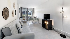 Un salon moderne avec un canapé, un téléviseur et une lampe sur pied.