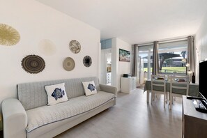 Una sala de estar moderna con sofá, mesa de comedor y decoración en la pared.