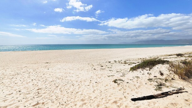 Une plage avec du sable, la mer et le ciel.