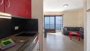 Une cuisine moderne avec des meubles rouges, un coin repas avec une table rouge et un balcon avec vue.