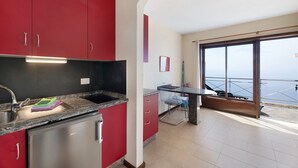Une cuisine avec des meubles de rangement rouges, un réfrigérateur en acier inoxydable et un coin repas comprenant une table et des chaises.