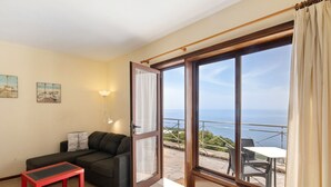 A room with a sofa, a small table, a balcony with a table and chairs, and a view of the sea. - Apartment 'Moijama 10' with Sea View, Shared Pool and Wi-Fi (Los Llanos de Aridane)