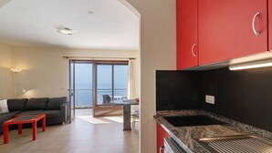 A modern kitchen with red cabinets, a dining area with a table and chairs, and a view to the outside. - Apartment 'Moijama 10' with Sea View, Shared Pool and Wi-Fi (Los Llanos de Aridane)