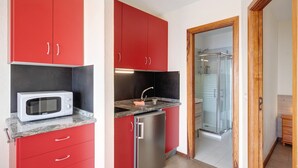 A compact kitchen with red cabinets, a microwave, a sink, and a refrigerator. - Apartment 'Moijama 10' with Sea View, Shared Pool and Wi-Fi (Los Llanos de Aridane)