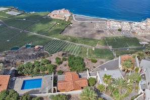 An aerial view of a coastal area with a large building complex, a swimming pool, and a vineyard. - Holiday Home 'Moijama 12' with Sea View, Shared Pool and Wi-Fi (Los Llanos de Aridane)