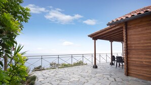 A stone patio with a wooden pergola, outdoor seating, and a view of the sea. - Holiday Home 'Moijama 12' with Sea View, Shared Pool and Wi-Fi (Los Llanos de Aridane)