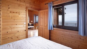 A wooden cabin room with a bed, a desk, and a window with curtains. - Holiday Home 'Moijama 12' with Sea View, Shared Pool and Wi-Fi (Los Llanos de Aridane)