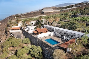 A coastal property with a swimming pool, stone walls, and a view of the sea. - Holiday Home 'Moijama 6' with Sea View, Shared Pool and Wi-Fi (Los Llanos de Aridane)