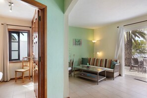 A room with a glass coffee table, wicker sofa, and a view of the outdoors. - Holiday Home 'Moijama 6' with Sea View, Shared Pool and Wi-Fi (Los Llanos de Aridane)