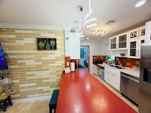 Una cocina moderna con encimera roja, armarios blancos y pared con diseño de ladrillo.