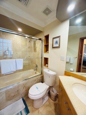 Une salle de bain avec une douche à parois de verre, des toilettes, un lavabo et un miroir.