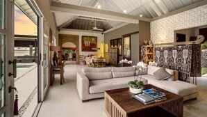 A spacious living area with a high ceiling, a large sofa, a coffee table, and a view of the outdoors. - Villa Eden Roc by Alfred in Bali (Karangasem)