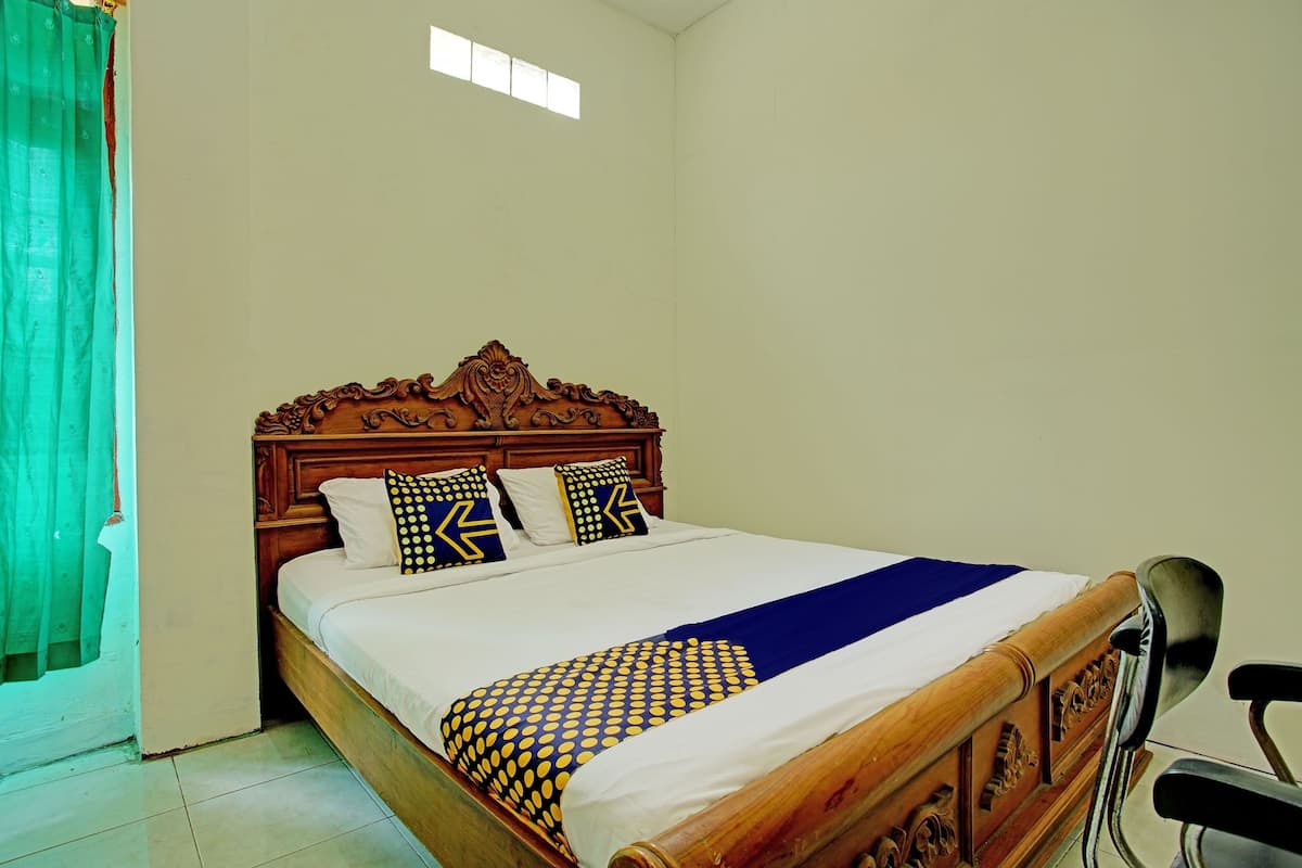 Una cama bien hecha con cabecera de madera, ropa de cama blanca y almohadas estampadas.