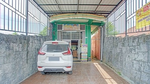 Een witte auto geparkeerd in een overdekte parkeergarage met een betegelde vloer, een groene boog en een bord voor een schoonheidssalon.