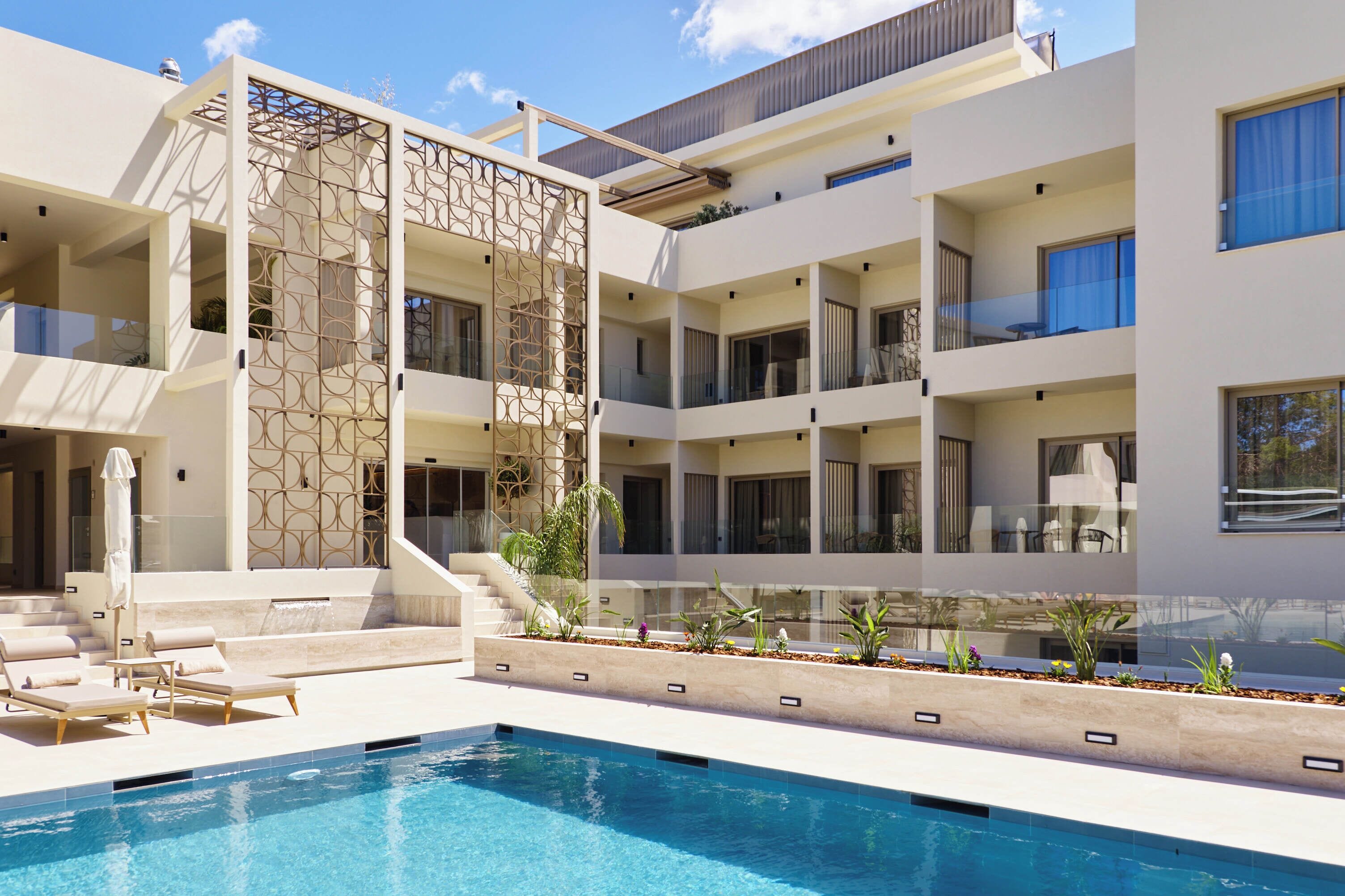 A modern hotel with a swimming pool, multiple balconies, and a decorative wall.