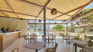An outdoor dining area with tables and chairs, a pool in the background, and a modern architectural design. - Inea Sole Boutique Hotel (Chania)