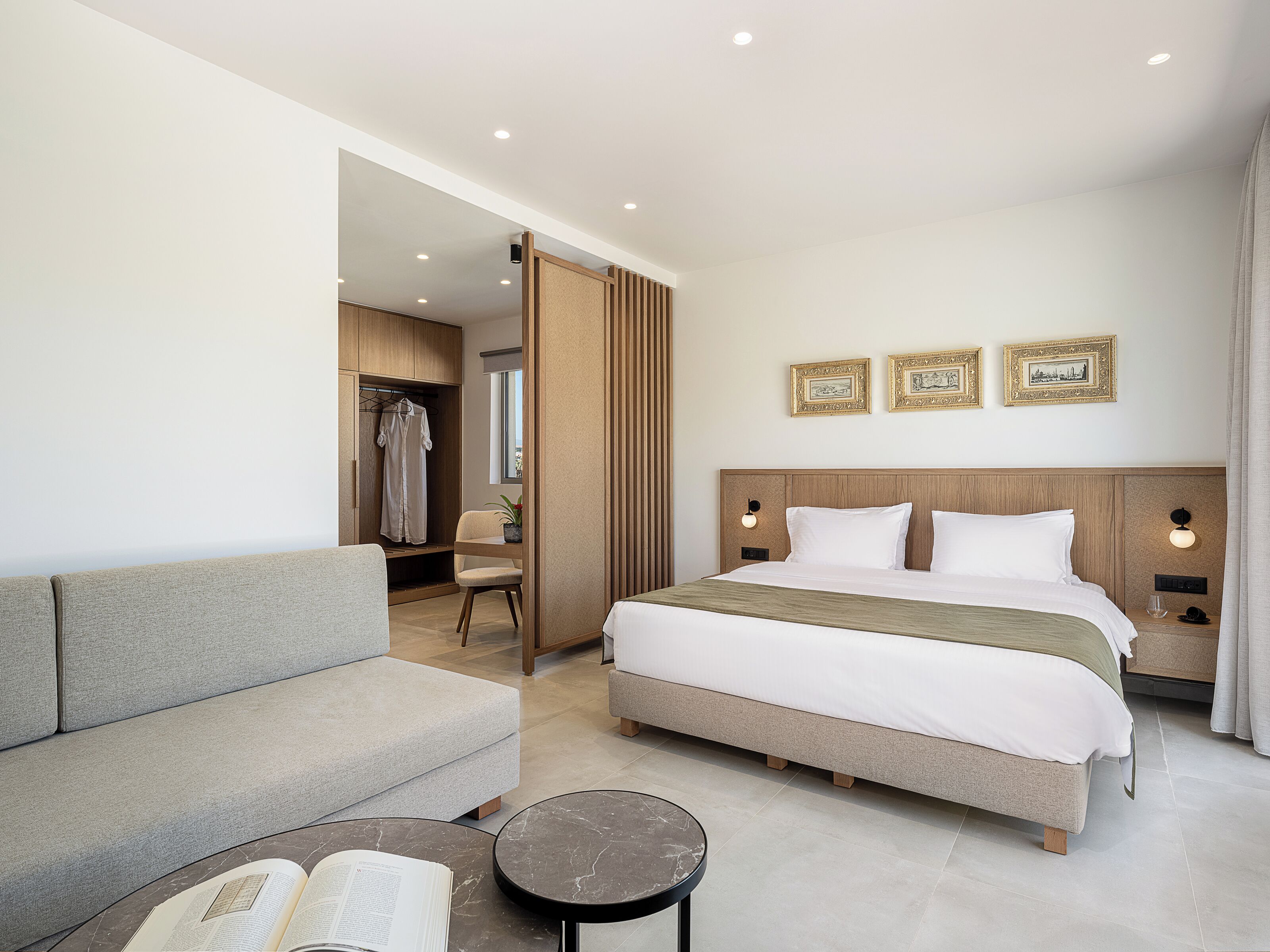 Une chambre d’hôtel moderne avec un grand lit, un canapé, une petite table et un dressing.
