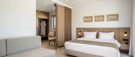 Une chambre d’hôtel moderne avec un grand lit, un canapé, une petite table et un dressing.