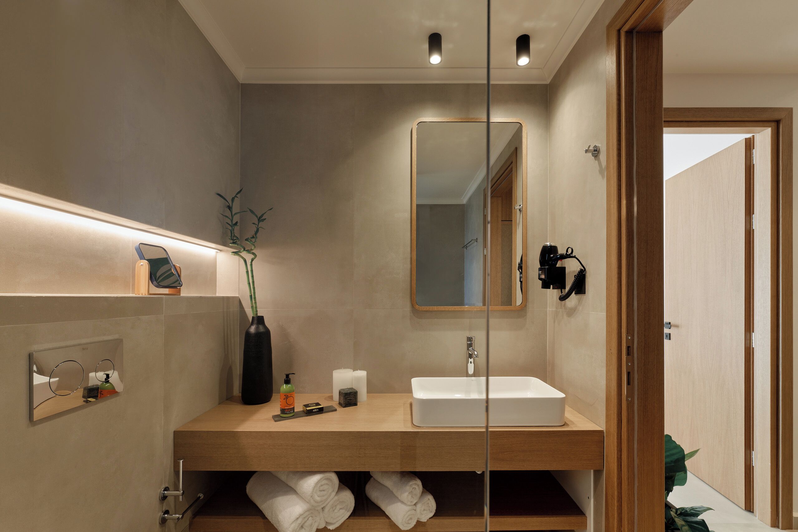 Un baño moderno con tocador de madera, un espejo grande y ducha integrada.