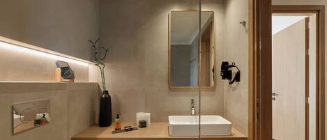 Un baño moderno con tocador de madera, un espejo grande y ducha integrada.