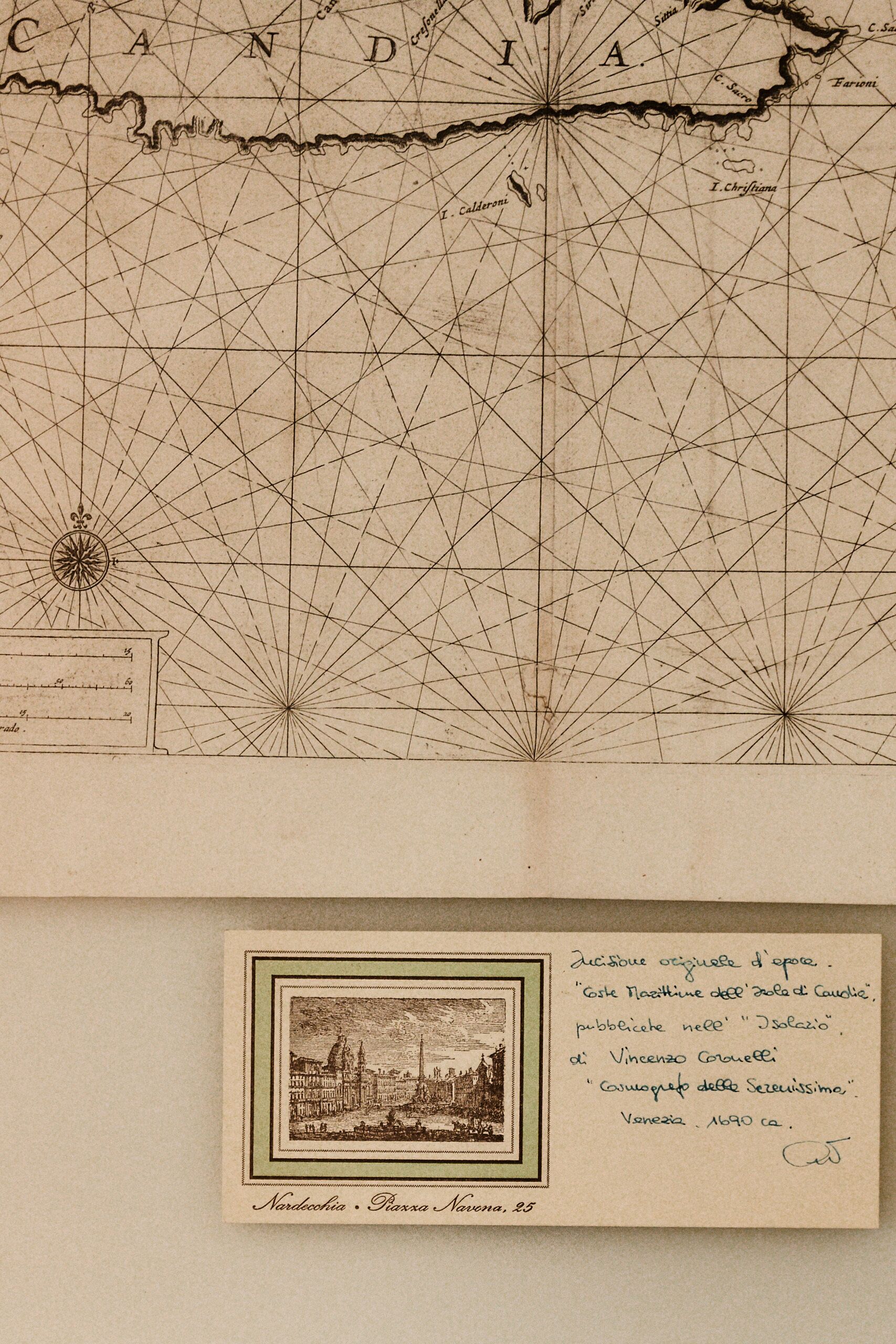 A vintage map with a compass rose and grid lines, and a framed historical illustration of a cityscape.