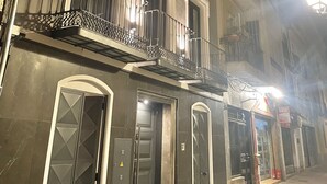 A multi-story building with a dark facade, multiple balconies, and a ground-level entrance with a glass door. - Apartamento Anaya 1, en Pleno Centro de Granada (Granada)