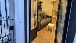 A modern living room with a sofa, a coffee table, and a glass door leading to a balcony. - Apartamento Anaya 1, en Pleno Centro de Granada (Granada)