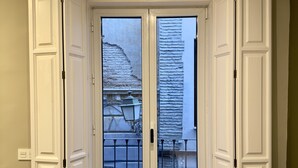 A room with a large sliding door leading to a balcony, a bed, and a sofa. - Apartamento Anaya 1, en Pleno Centro de Granada (Granada)