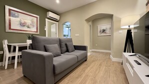 A modern living room with a grey sofa, a white table, and a lamp. - Apartamento Anaya 1, en Pleno Centro de Granada (Granada)