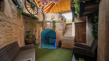 Un intérieur rustique avec des murs en pierre, un plafond en bois et un portail bleu portant l’inscription « DANGER ».