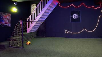 Ein Zimmer mit Fußballtor, einer Treppe und einer Wand mit Neonlichtern.
