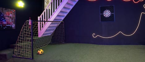 A room with a soccer goal, a staircase, and a wall with neon lights.