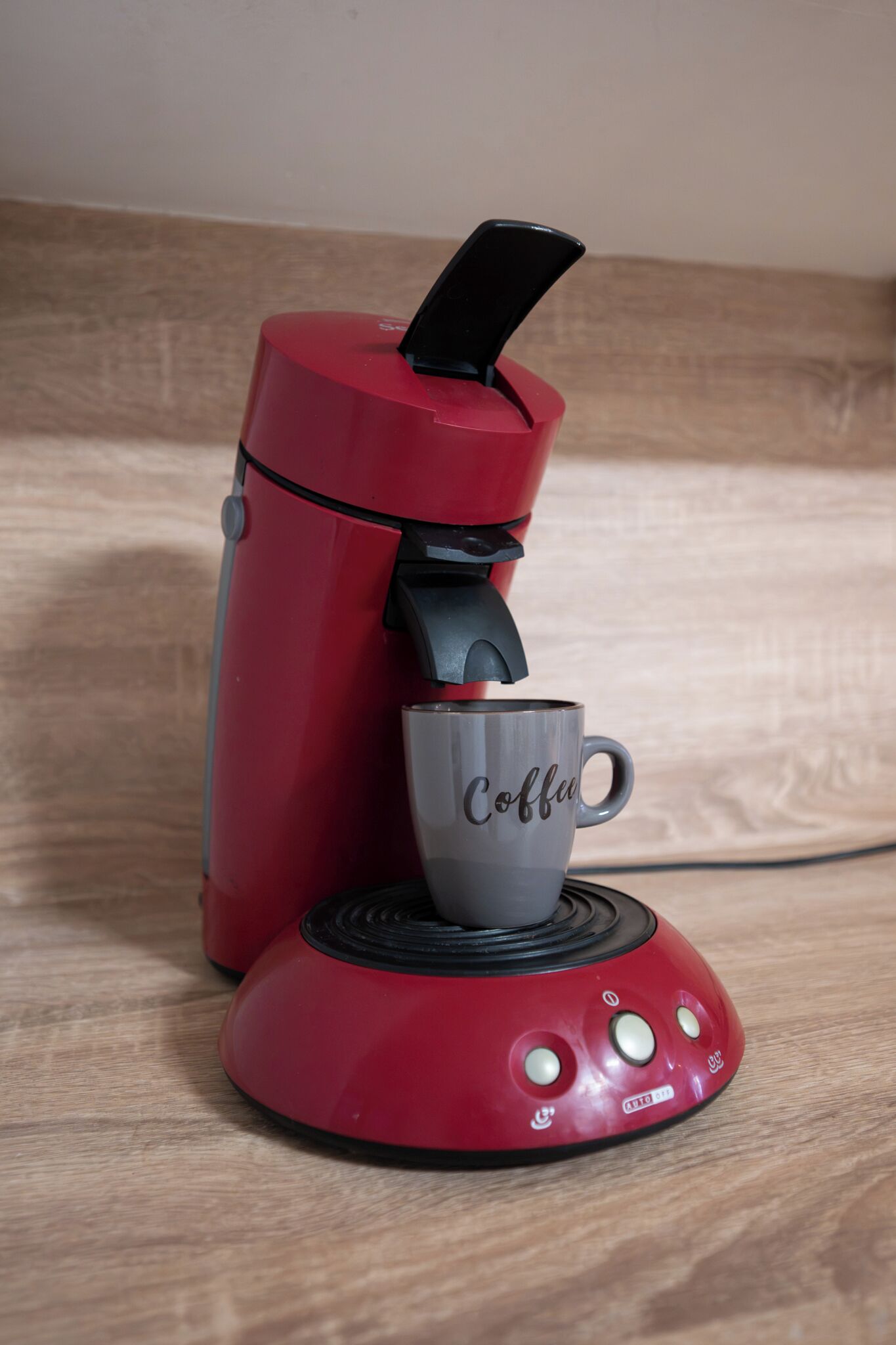 Een rode koffiezetapparaat met een kop koffie erop.